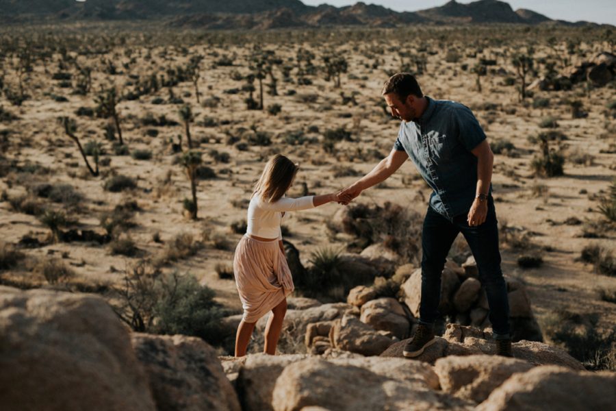 Couple holding hands on rocks, engagement pictures with a view, Moody Couples Session at Joshua Tree