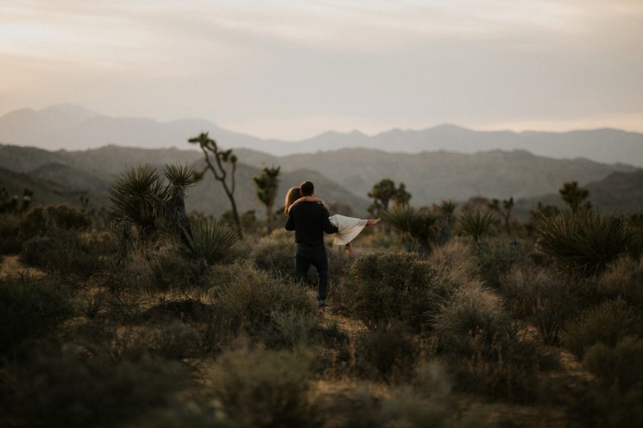 man carrying woman outside, romantic couple posing, Moody Couples Session at Joshua Tree