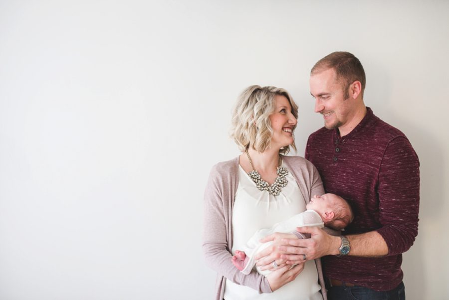 Couple looking at each other and holding newborn, Clean and Simple Newborn Portraits