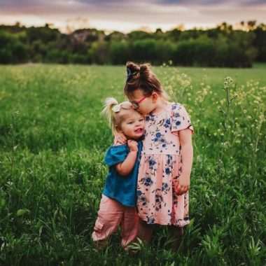 Portrait of sisters hugging in grassy field, Daily Fan Favorite on Beyond the Wanderlust