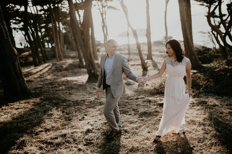 couple walking through wooded beach area, picture of man and woman holding hands and walking, San Francisco Beach Engagement Photos