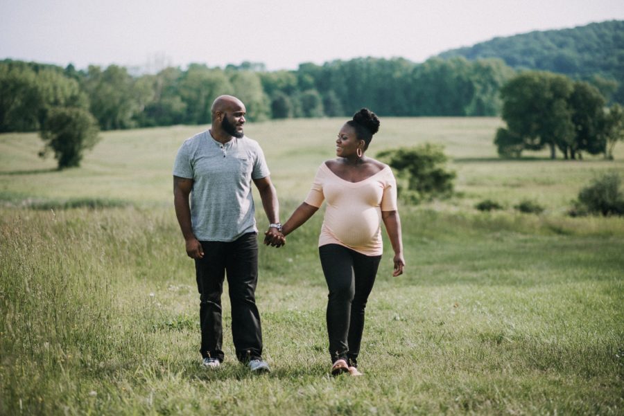 Couple holding hands and walking through open field, Classy Outdoor Maternity Session in Philadelphia