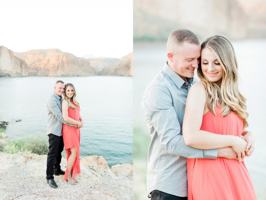 Man behind woman with arms wrapped around waist, Couple smiling on rocks overlooking lake, Canyon Lake Engagement Pictures in Arizona