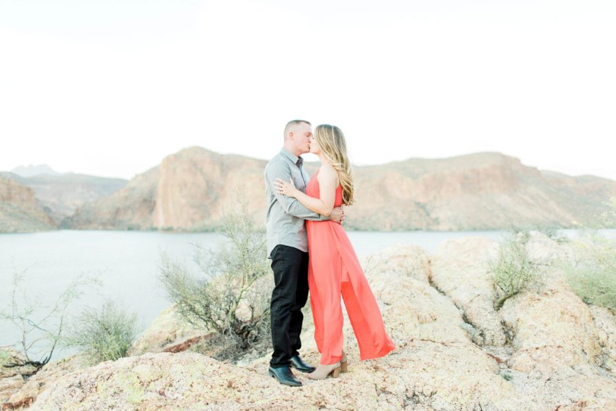 Couple kissing on rocks above lake, Red rocks surrounding lake, Canyon Lake Engagement Pictures in Arizona