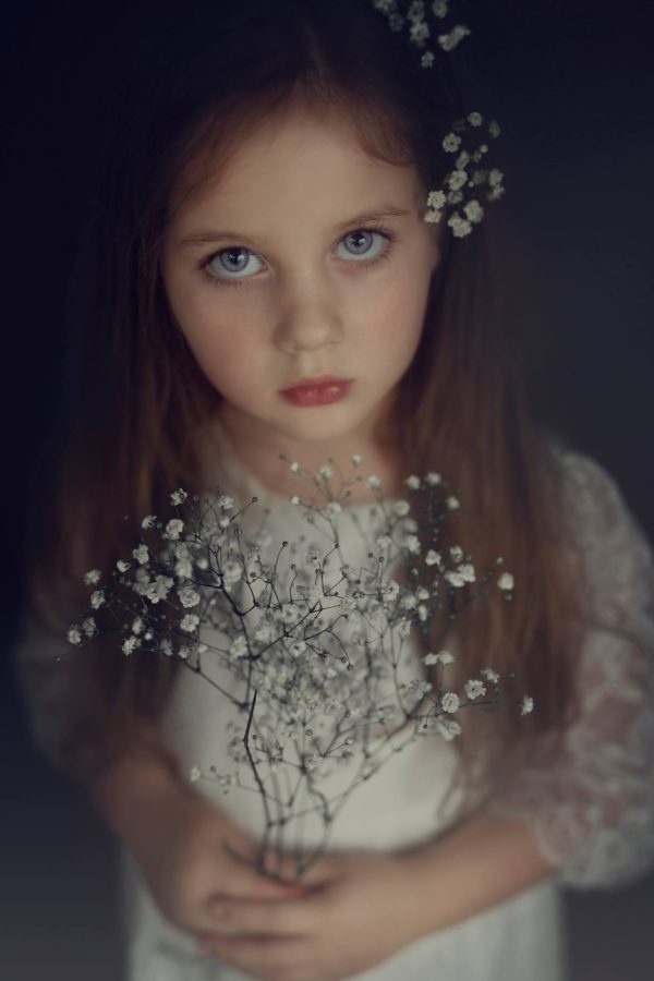 Portrait of girl looking at camera holding little white flowers, Beyond the Wanderlust Daily Fan Favorite