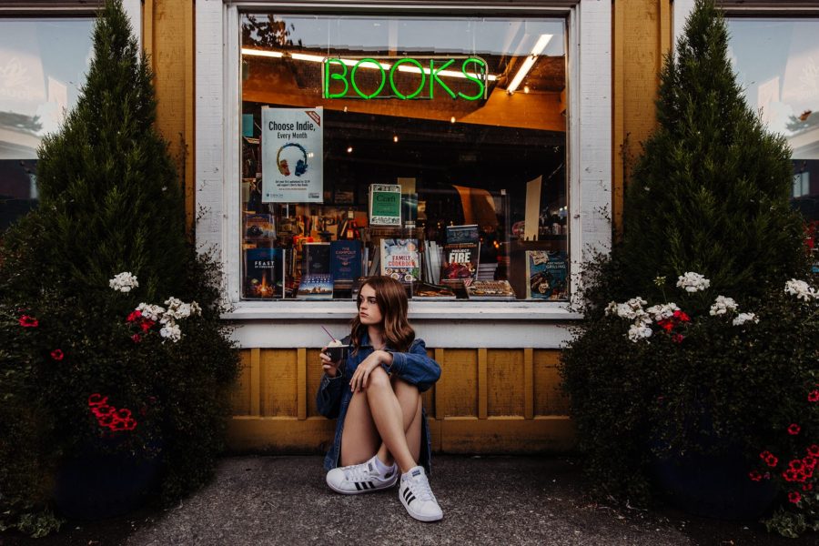 Girl sitting on ground with ice cream, girl outside of bookstore, Beyond the Wanderlust Daily Fan Favorite