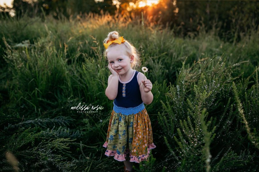 Little girl holding wildflower and smiling with hand on cheek, Melissa Rosic Photography Daily Fan Favorite