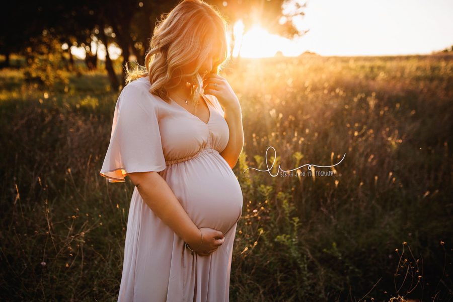 Woman standing in field with golden sun behind her holding her pregnant belly, Bekah Jane Photography Daily Fan Favorite