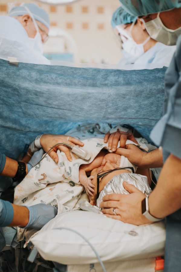 Newborn on moms chest reaching up to her face right after c-section, Beyond the Wanderlust Daily Fan Favorite