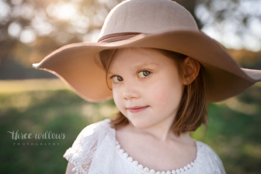Portrait of girl looking at camera with sly grin under brim of hat, Beyond the Wanderlust Daily Fan Favorites