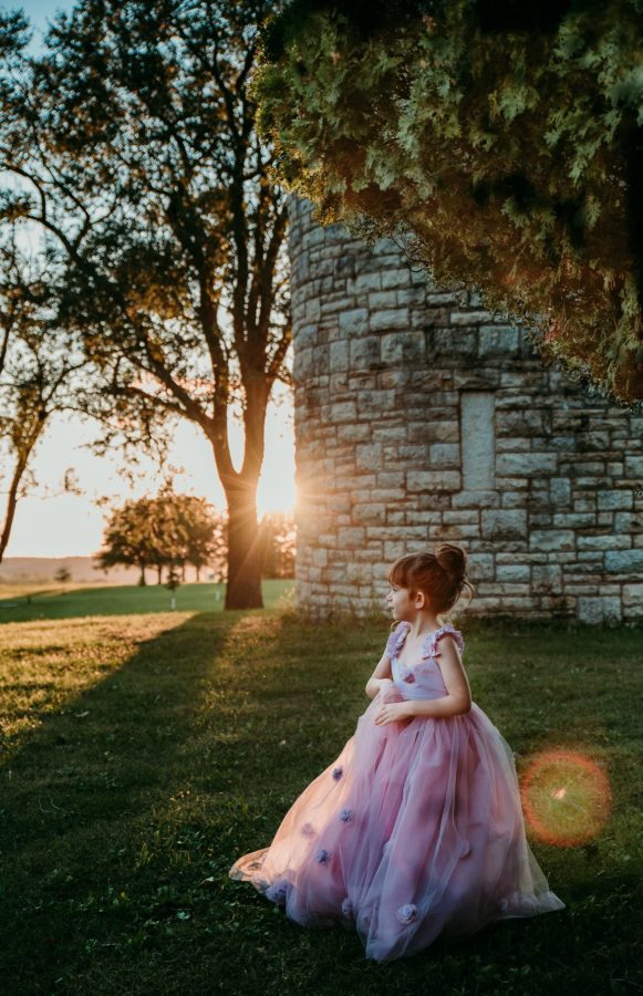 Girl in purple dress standing in grass with sun flare in background, Beyond the Wanderlust Daily Fan Favorites