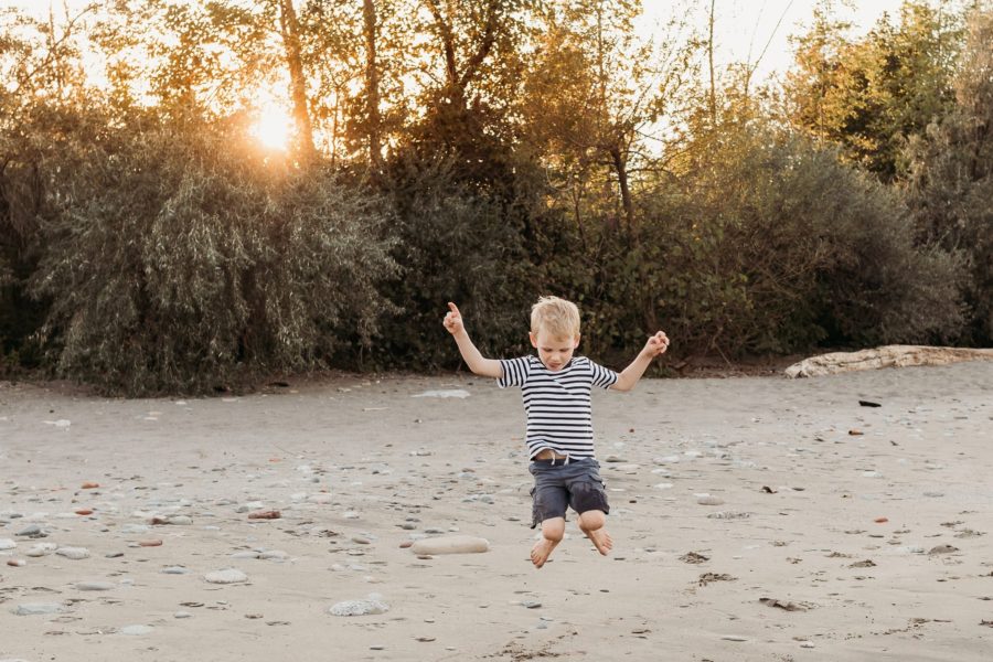 Boy jumping in sand with golden light behind him in trees, Beyond the Wanderlust Daily Fan Favorites