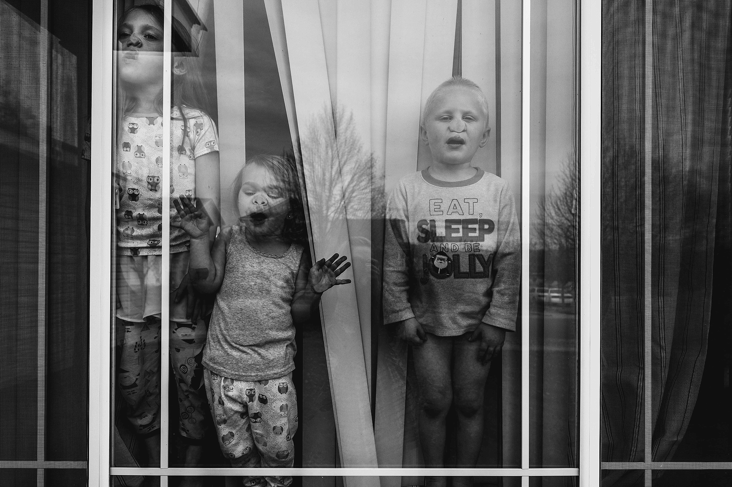 black and white kid pictures, lifestyle and documentary photography, kids in window being funny