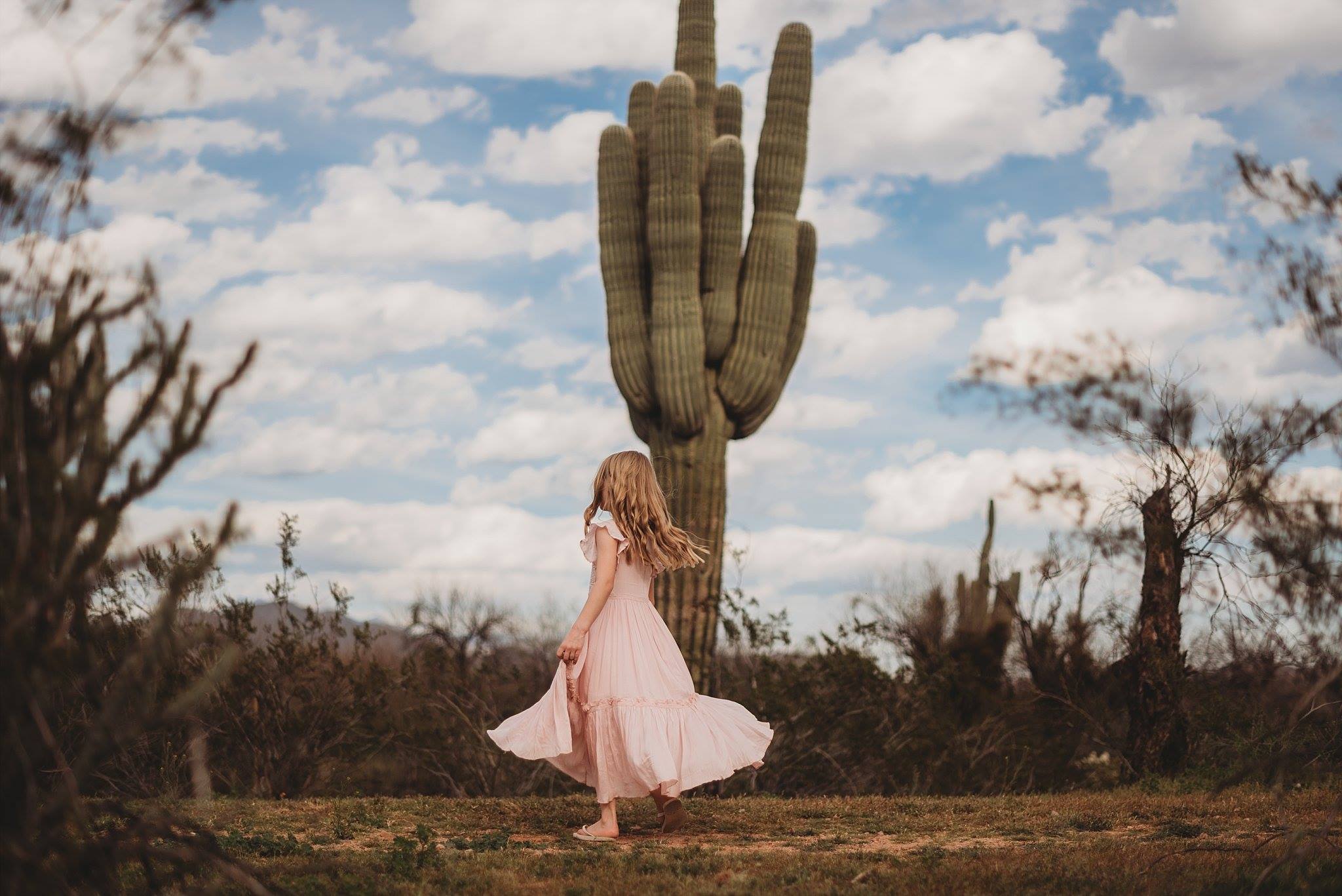 spring pictures of kids, little girl twirling in pink dress, arizona spring, little girl dancing in the dessert