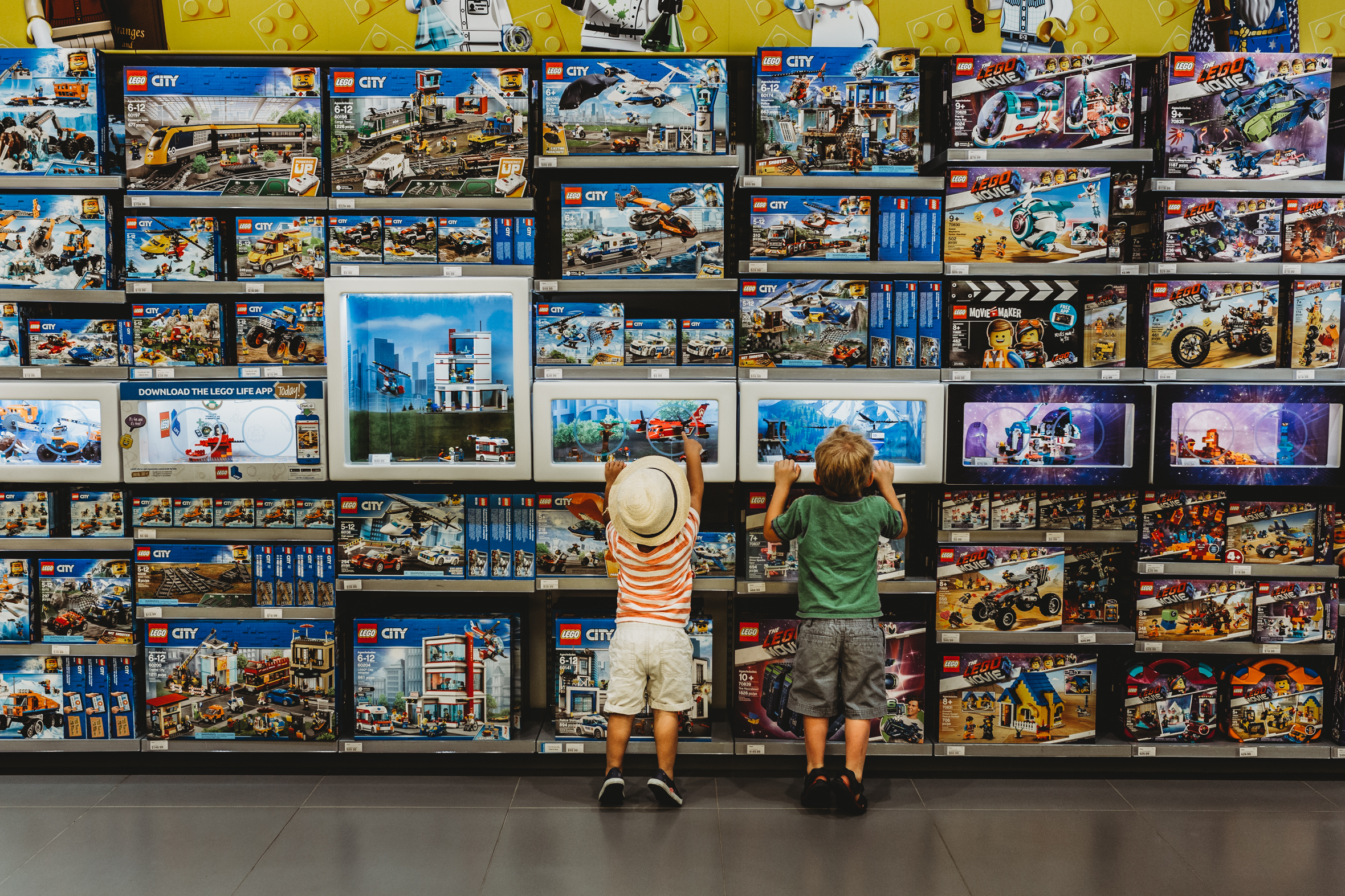 two boys looking at lego wall - shopping at toy store - lifestyle kids